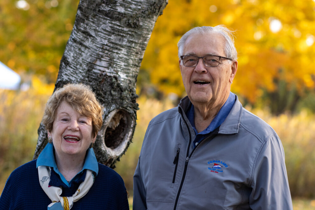 Smiling couple outside with fall leaves in the background